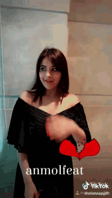 a woman in a black off the shoulder dress is holding a broken heart with the word anmolfeat on the bottom