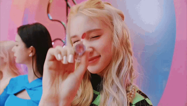 a woman with blonde hair is holding a small object in her hand and making a face .