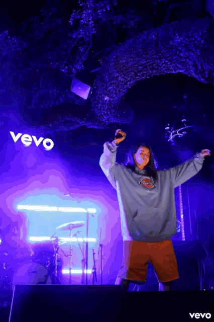 a person on stage with a microphone in front of a vevo sign