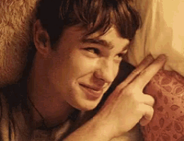 a young man is laying on a bed with his hand on his face .