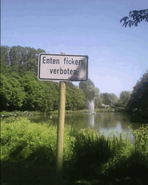 a sign that says ' etten ficken verboten ' in front of a pond