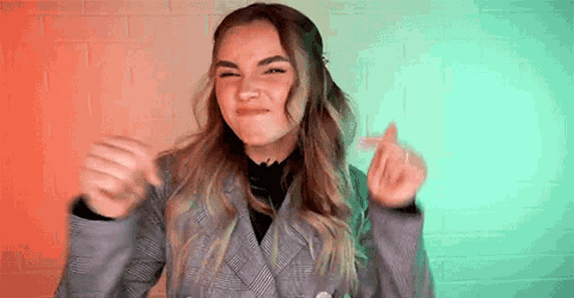 a woman in a suit is making a funny face and making a heart with her hands .