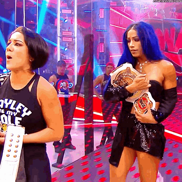 a woman with blue hair is holding a championship belt