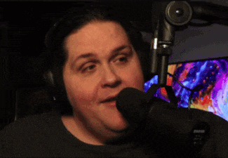 a man wearing headphones and a shure microphone is smiling