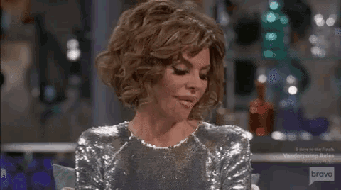a woman is sitting at a table wearing a silver sequined dress .