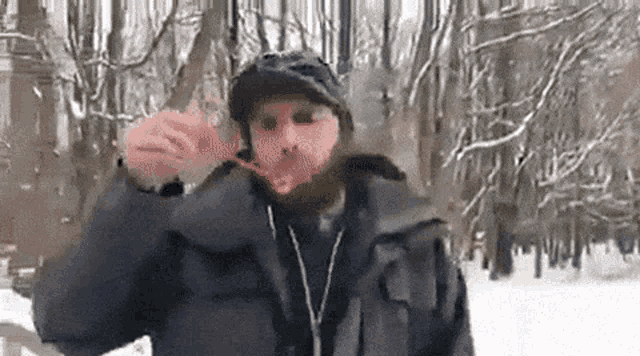a man with a beard is brushing his teeth in the snow while wearing headphones .
