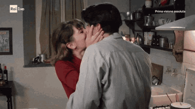a man and woman kissing in a kitchen with rai 1 hd