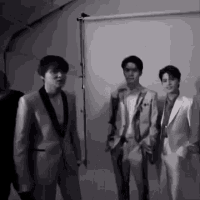 a group of men in suits are standing next to each other in a black and white photo .