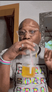 a man wearing glasses is drinking from a plastic cup