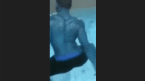 a man is swimming in a pool with a blue shirt on .