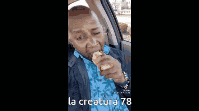a man is sitting in a car eating a hot dog with the number 78 on the bottom