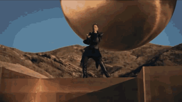 a woman standing in front of a large gold ball