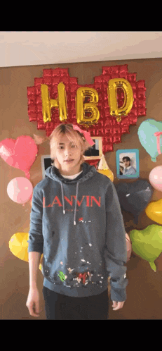 a man wearing a lanvin hoodie is standing in front of balloons