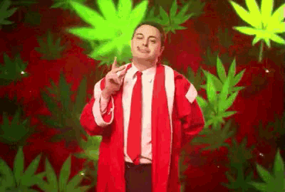 a man in a santa coat and tie is smoking a cigarette in front of a marijuana background .