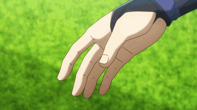 a close up of a person 's hand on a green field