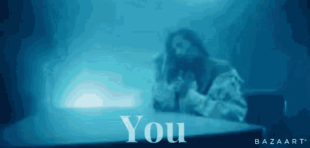 a blurred image of a person sitting at a table with the words you below them