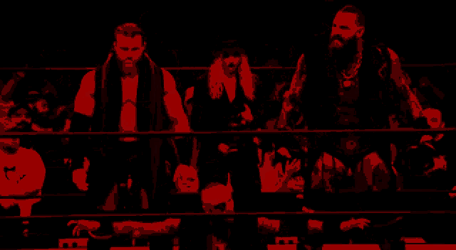 a group of wrestlers standing in a ring with a referee behind them