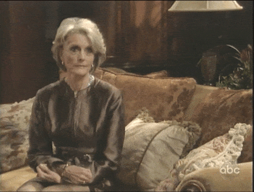 a woman is sitting on a couch with abc written on the bottom