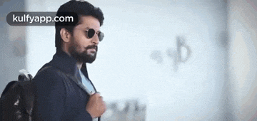 a man with a beard is wearing sunglasses and a black jacket .