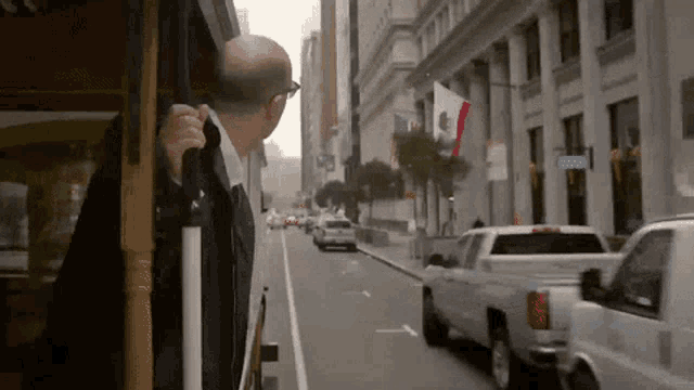 a man in a suit is riding a trolley down a city street