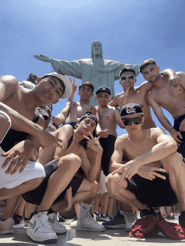 a group of young men are posing for a picture in front of a statue of jesus