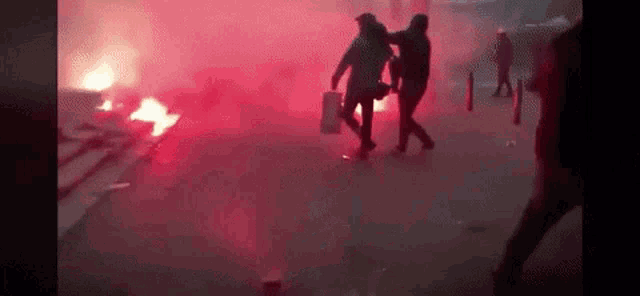 a group of people are walking through a smokey area with a fire in the background .