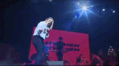 a woman singing in front of a sign that says hen on it
