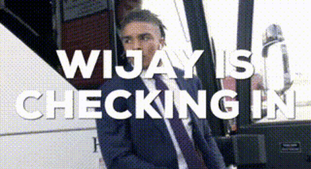 a man in a suit and tie stands in front of a sign that says " wijay is checking in "