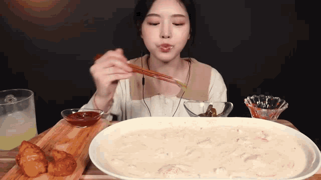 a woman with chopsticks is eating a large plate of food