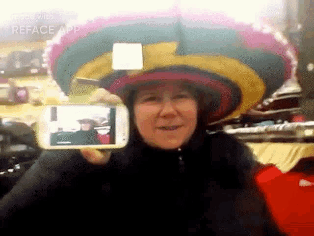 a woman wearing a sombrero is taking a picture of herself on her phone