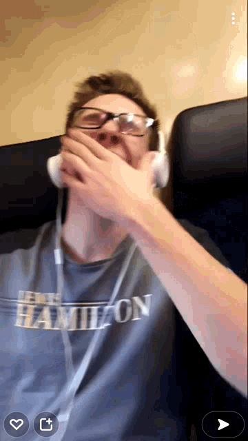 a man wearing a hamilton shirt is covering his mouth