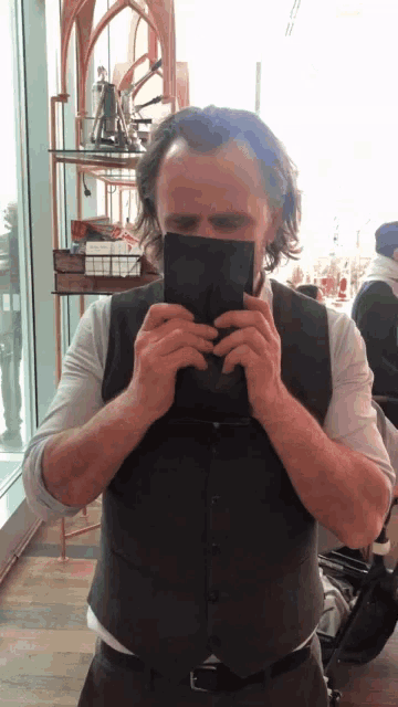 a man in a vest is holding a piece of paper in his hands
