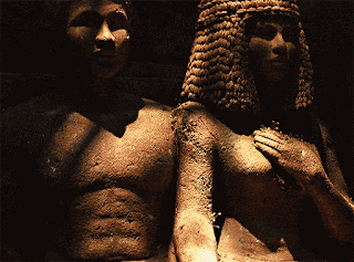 a statue of a man and a woman standing next to each other in a dark room