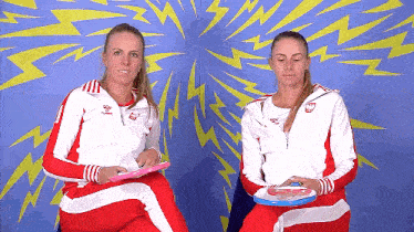 two women sitting next to each other in front of a blue wall with lightning bolts
