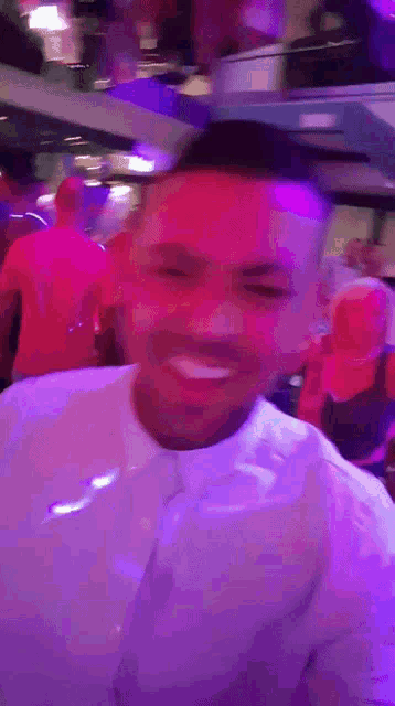 a man in a white shirt is smiling in a club