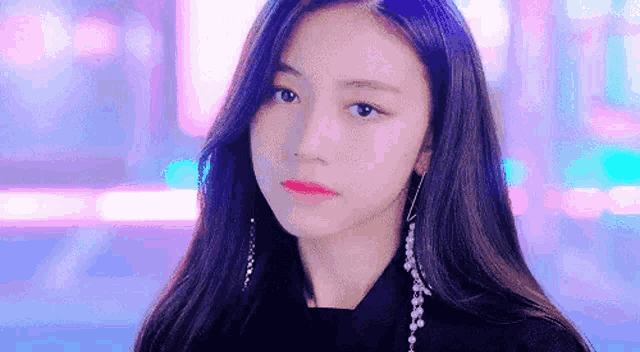 a close up of a young woman wearing a black shirt and earrings .