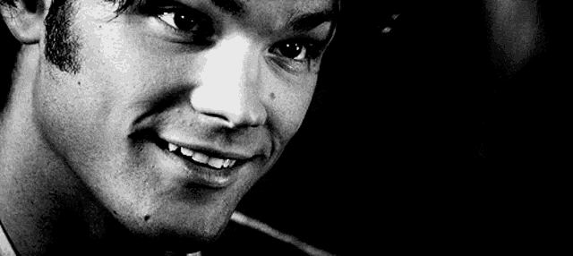 a black and white photo of a young man smiling .
