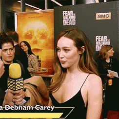 a woman holding a microphone in front of a fear of the walking dead sign