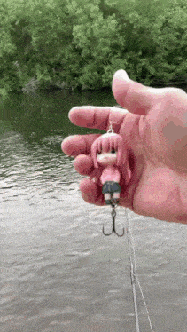 a person is holding a fishing hook with a pink doll on it