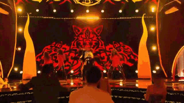 a group of people are dancing on a stage with a tiger on it 's back .