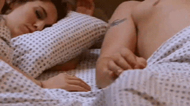 a woman is sleeping next to a man in a hospital bed