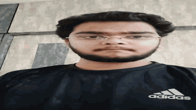 a man with a beard wearing a black adidas shirt