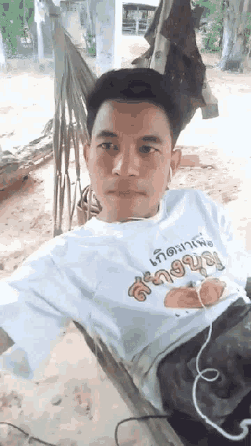 a man laying in a hammock wearing a shirt that says ' a ' on the front