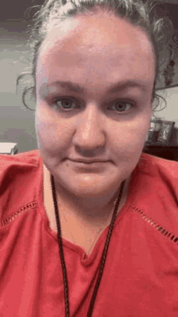 a woman in a red shirt is making a funny face while looking at the camera .