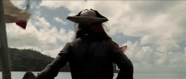 a man in a pirate costume is standing on a boat in the water .