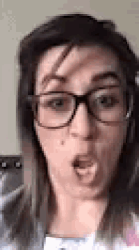 a close up of a woman wearing glasses and making a funny face .