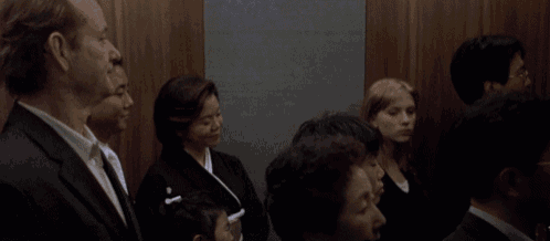 a group of people are standing in an elevator with a man in the middle