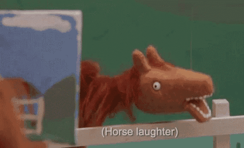 a stuffed horse is standing behind a fence with its mouth open and says horse laughter .