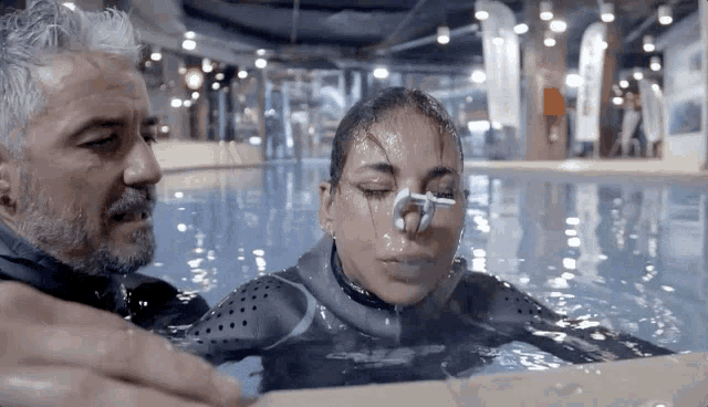 a man and a woman in a swimming pool with their eyes closed