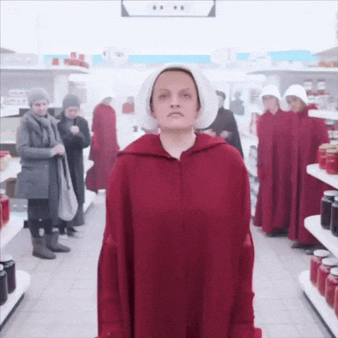 a woman in a red cape and white hat stands in a grocery store surrounded by other women